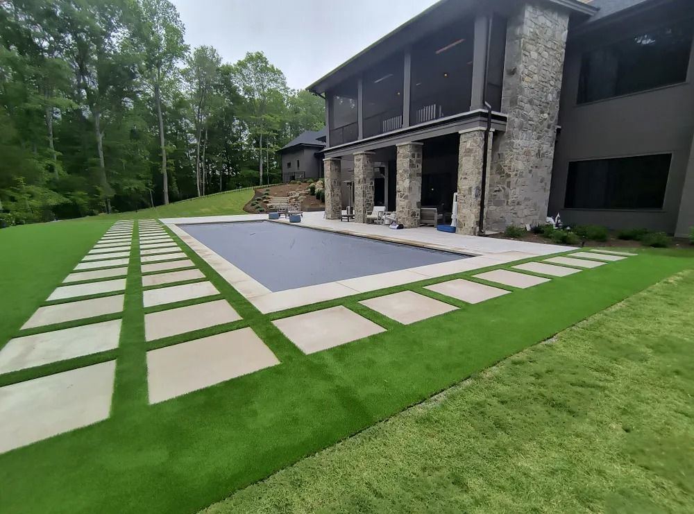 Turf lawn and pavers beside a pool