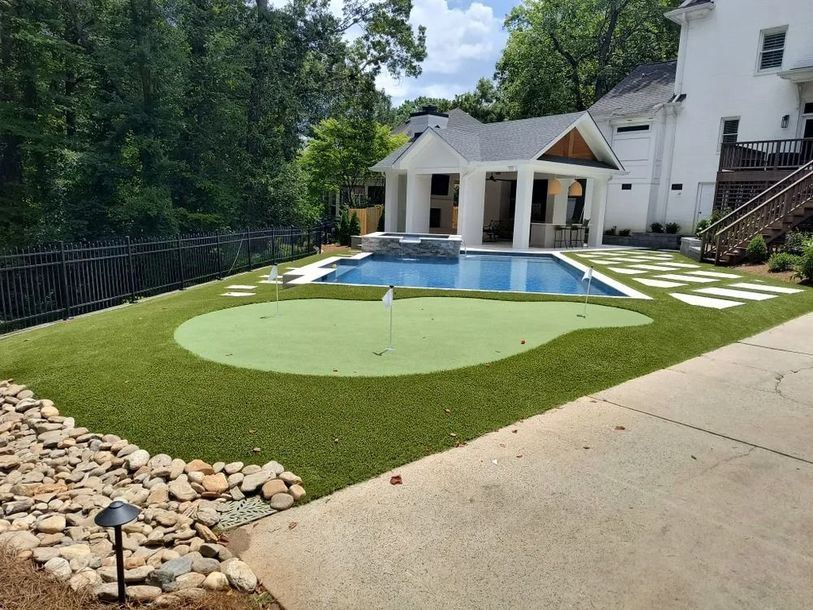 Putting green beside a backyard pool